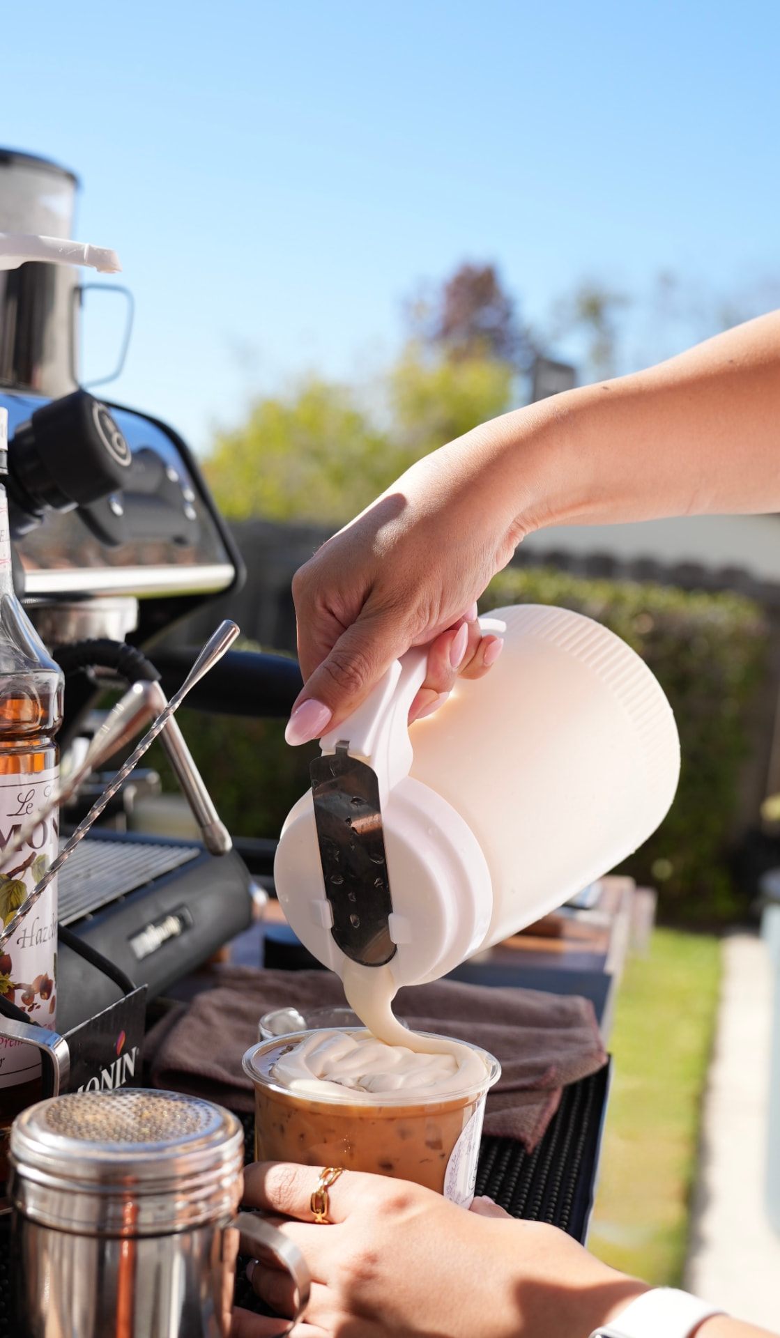 Barista pouring a cream top onto a latte
